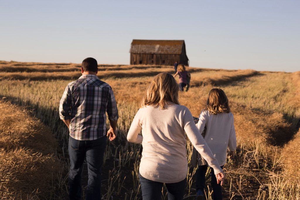 Family with their backs to us walking through a field